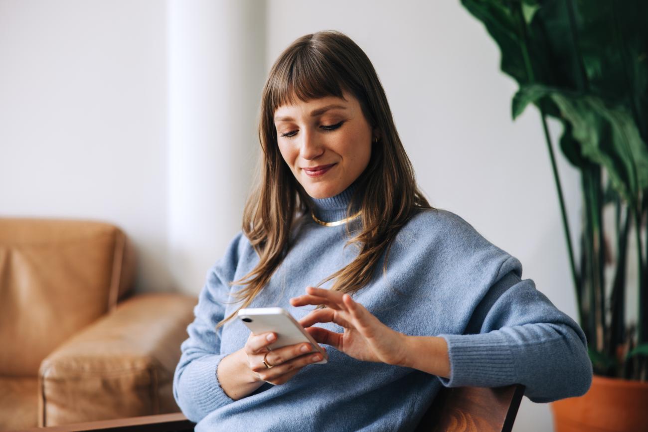 Vrouw meldt eenvoudig schade via smartphone vanuit huis als onderdeel van snelle en persoonlijke schadeafhandeling van Hoogkamer Assurantiën.